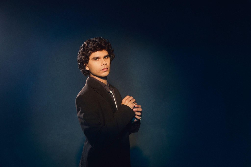 El cantante australiano Budjerah posando de forma elegante con un traje gris