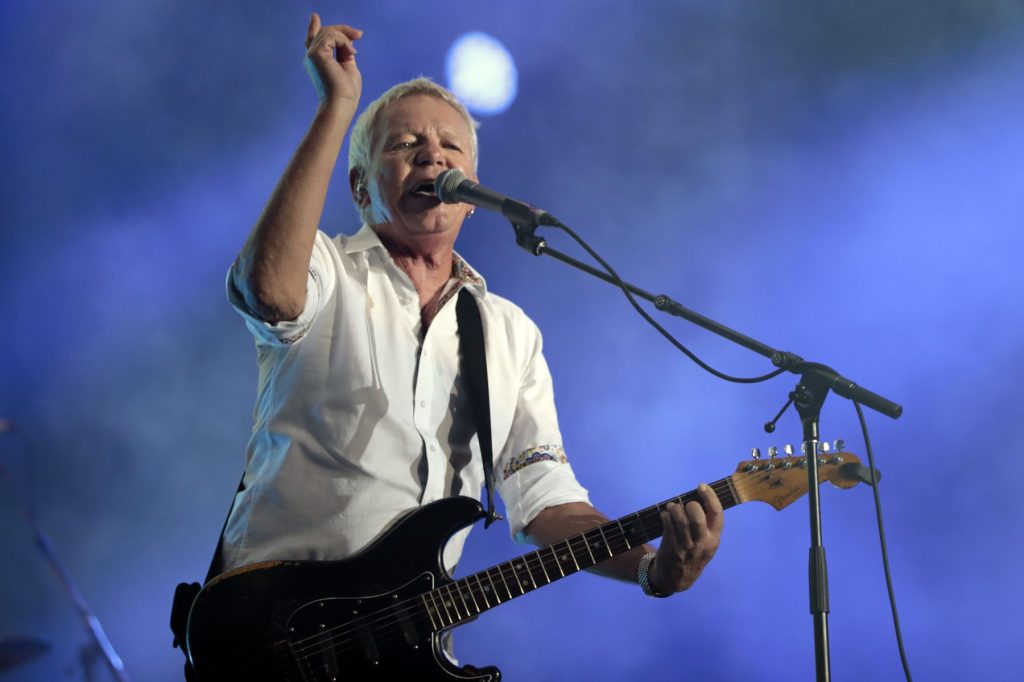 Iva Davies, líder de la banda Icehouse, cantando en directo sobre un escenario.