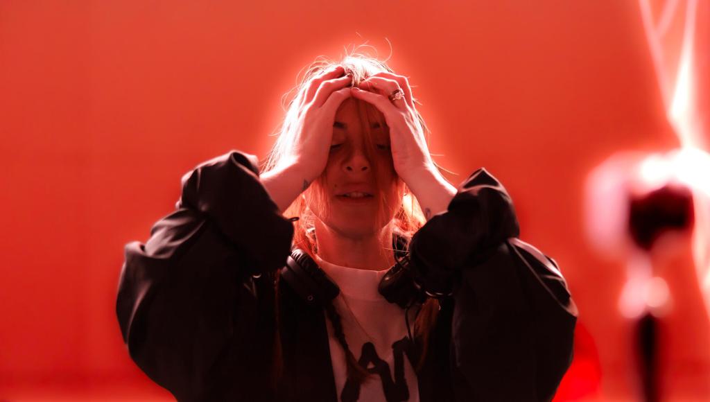 Alison Wonderland sonriendo y emocionada, vistiendo ropa deportiva de Adidas con los colores de Australia, posiblemente en un estudio o junto a un balón de fútbol.