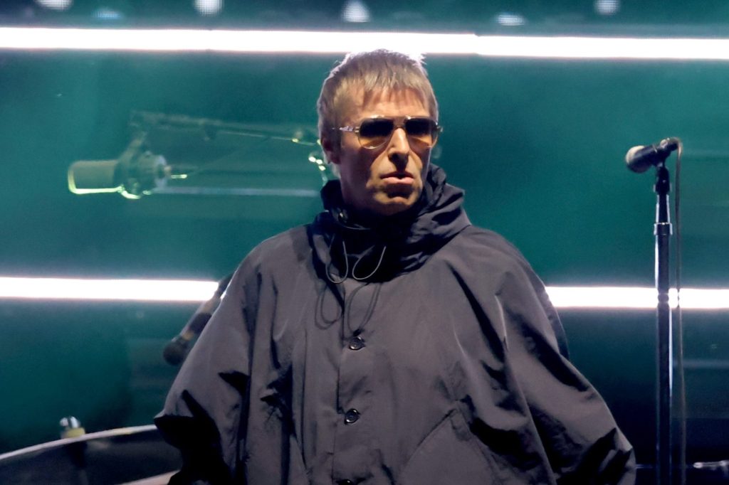 Liam Gallagher cantando en un escenario con un micrófono en la mano durante un concierto.
