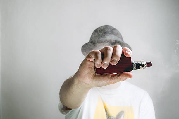 Joven utilizando un dispositivo de vapeo al aire libre