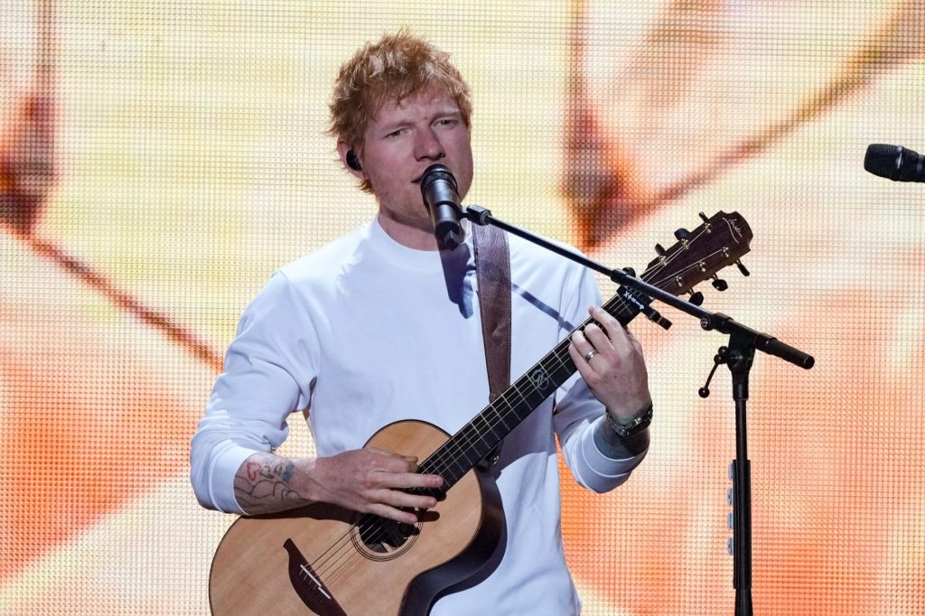 Ed Sheeran tocando la guitarra en directo sobre el escenario.
