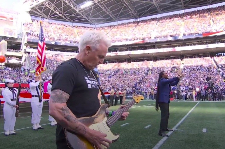 Mike McCready tocando la guitarra eléctrica durante el himno nacional en un partido de la NFL